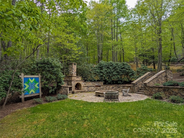 view of yard featuring an outdoor stone fireplace and a patio area