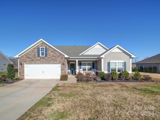 view of front of home featuring a porch, a garage, and a front lawn