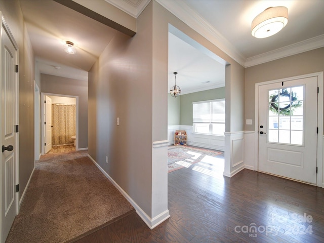 entryway featuring dark hardwood / wood-style flooring, crown molding, and a chandelier