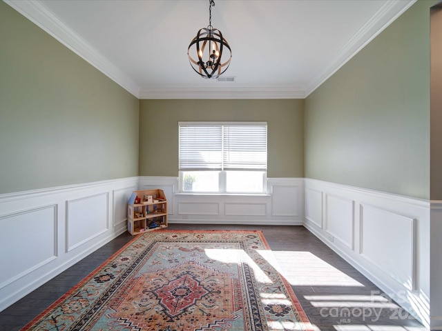 spare room with ornamental molding, dark wood-type flooring, and an inviting chandelier