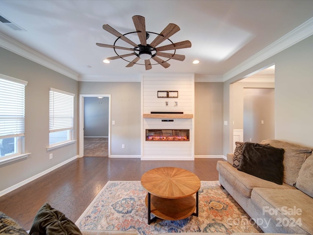 living room with dark wood-type flooring, ceiling fan, a fireplace, and crown molding