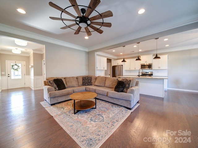 living room featuring dark hardwood / wood-style floors, ceiling fan, ornamental molding, and sink