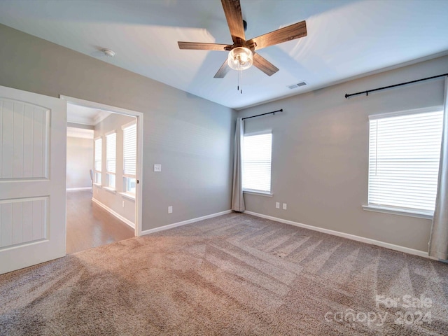 carpeted spare room featuring plenty of natural light and ceiling fan