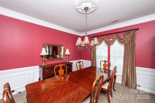 carpeted dining room with crown molding and a chandelier