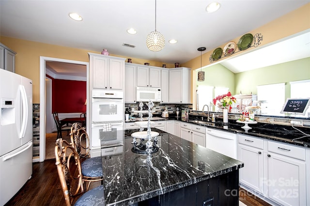 kitchen featuring white appliances, hanging light fixtures, dark stone countertops, and sink