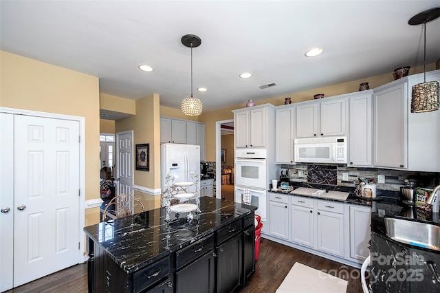 kitchen featuring decorative backsplash, a center island, hanging light fixtures, and white appliances