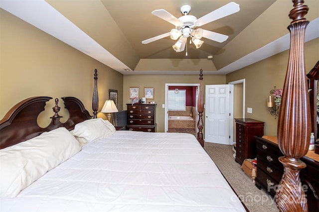 bedroom featuring a tray ceiling, ensuite bath, ceiling fan, and carpet