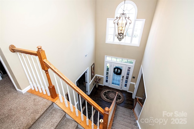 foyer featuring a high ceiling, carpet floors, and an inviting chandelier