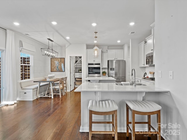 kitchen with sink, white cabinetry, hanging light fixtures, and appliances with stainless steel finishes