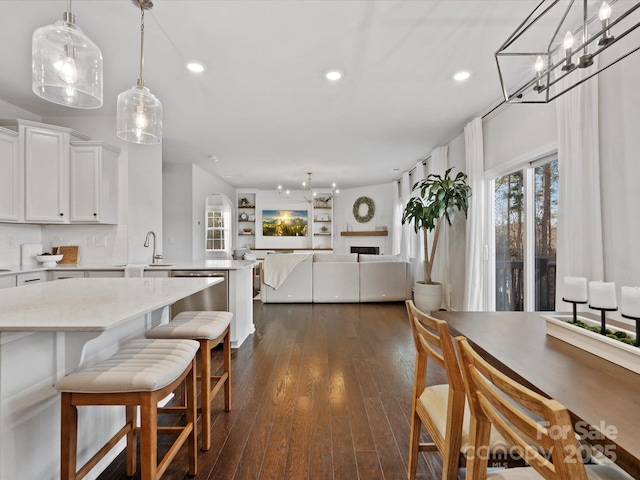 kitchen featuring white cabinets, decorative light fixtures, stainless steel dishwasher, decorative backsplash, and dark hardwood / wood-style floors