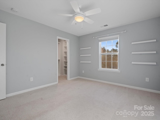 unfurnished bedroom with ceiling fan, a spacious closet, a closet, and light carpet