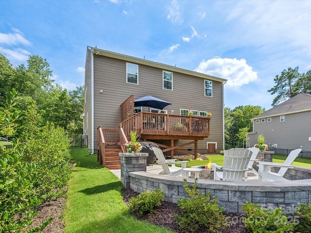 rear view of property featuring a fire pit, a wooden deck, and a patio area