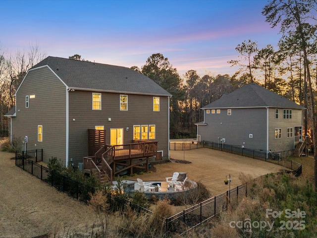 back house at dusk with a fire pit and a wooden deck