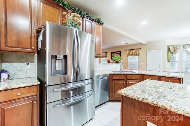 kitchen featuring decorative backsplash, sink, light stone counters, and stainless steel appliances