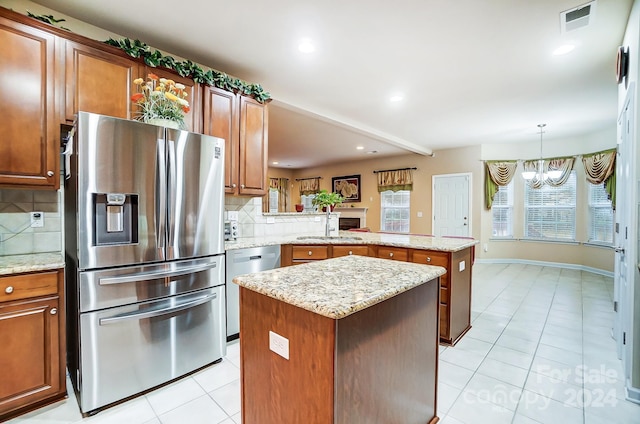 kitchen with kitchen peninsula, appliances with stainless steel finishes, tasteful backsplash, an inviting chandelier, and a center island