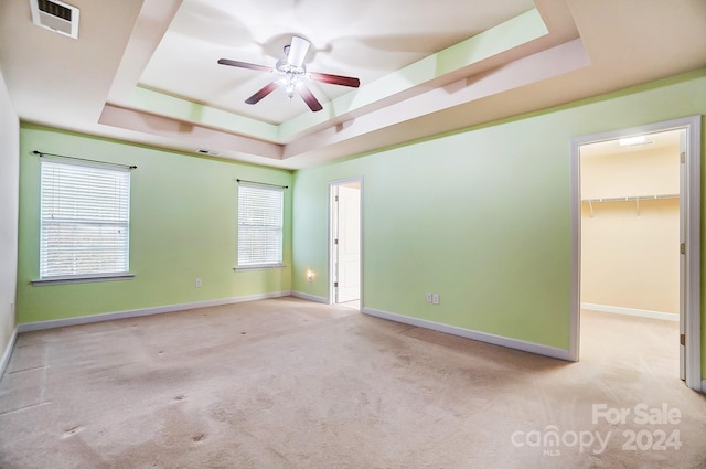 unfurnished room featuring ceiling fan, a raised ceiling, and light colored carpet