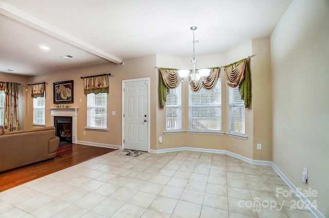 unfurnished dining area featuring beamed ceiling, an inviting chandelier, light hardwood / wood-style flooring, and a healthy amount of sunlight