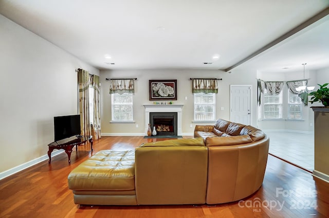 living room featuring beamed ceiling, hardwood / wood-style floors, and an inviting chandelier