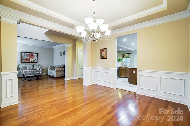 unfurnished dining area with crown molding, wood-type flooring, and an inviting chandelier