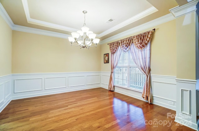 unfurnished room with a chandelier, hardwood / wood-style floors, a raised ceiling, and ornamental molding