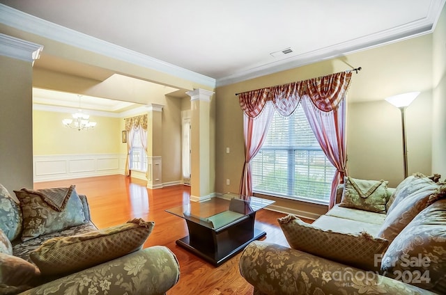 living room with hardwood / wood-style flooring, decorative columns, ornamental molding, and a chandelier