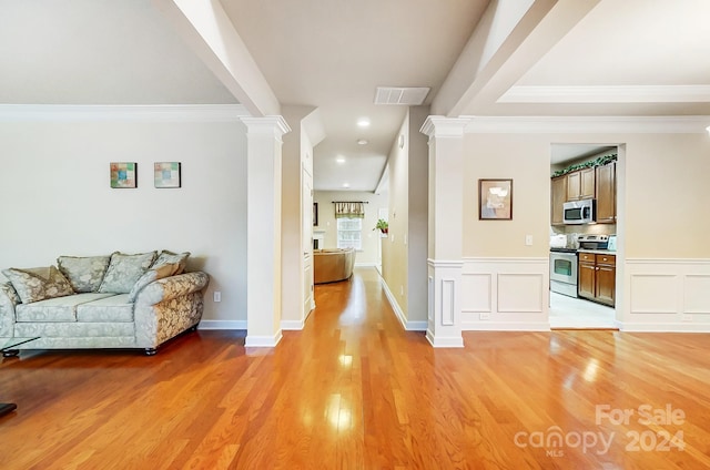 interior space featuring decorative columns, crown molding, and light wood-type flooring