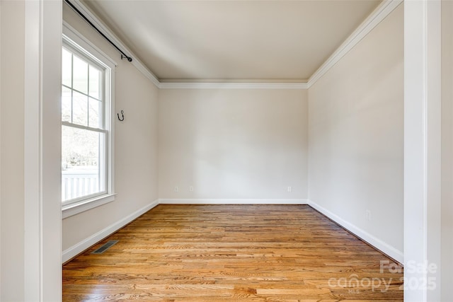 empty room with a healthy amount of sunlight, crown molding, and light hardwood / wood-style flooring