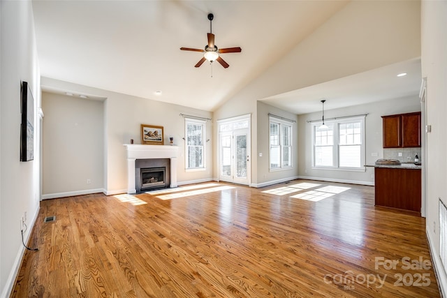 unfurnished living room with light wood-type flooring, high vaulted ceiling, and ceiling fan