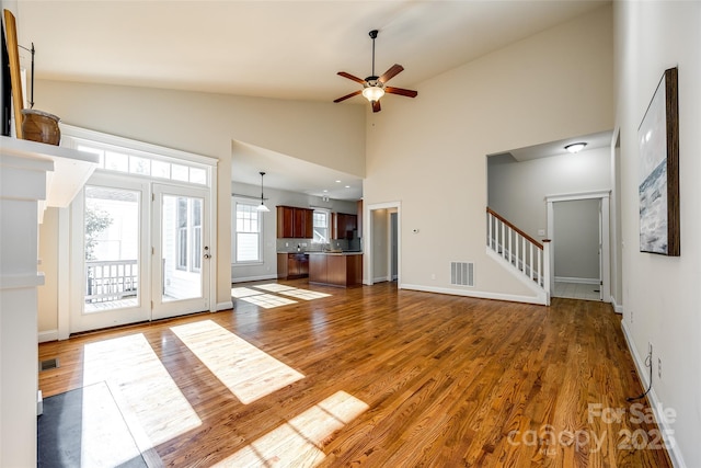 unfurnished living room with wood-type flooring, high vaulted ceiling, and ceiling fan