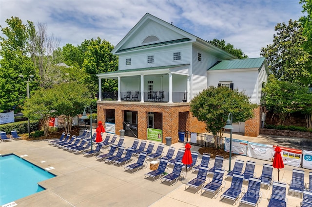 back of house featuring a patio area, a balcony, and a community pool