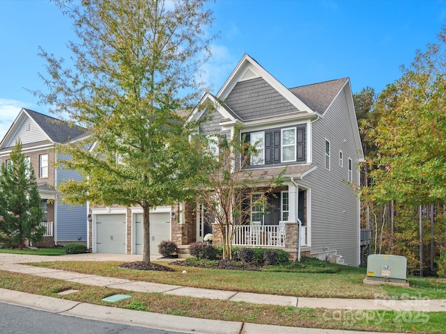 view of front of property featuring a porch, a garage, and a front lawn