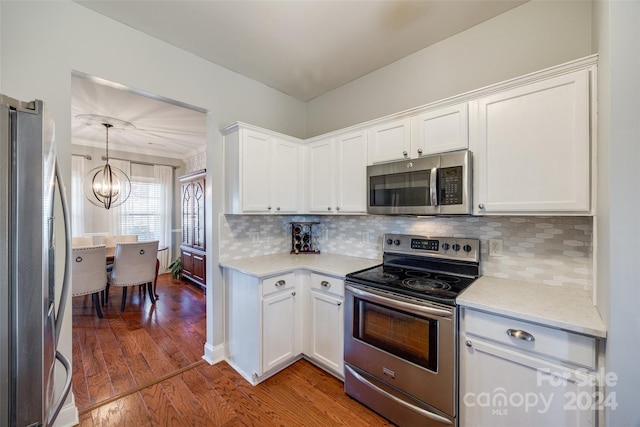 kitchen with white cabinets, appliances with stainless steel finishes, a notable chandelier, and wood-type flooring