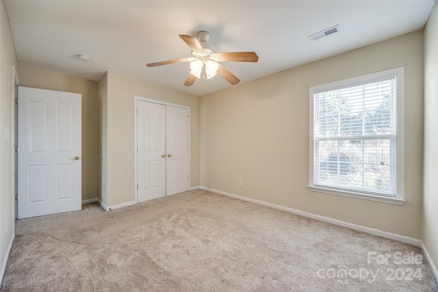 unfurnished bedroom featuring ceiling fan, light carpet, and a closet