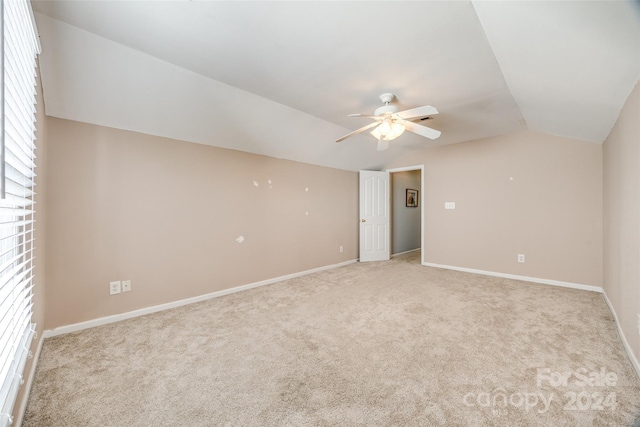 carpeted spare room featuring ceiling fan and vaulted ceiling