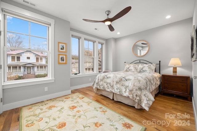 bedroom with multiple windows, hardwood / wood-style flooring, and ceiling fan