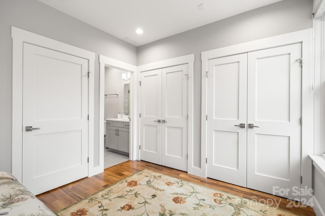 interior space with light wood-type flooring, connected bathroom, and two closets