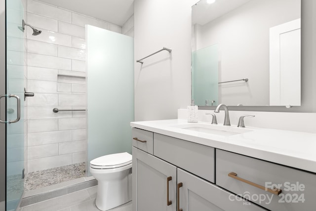 bathroom with tile patterned floors, vanity, an enclosed shower, and toilet