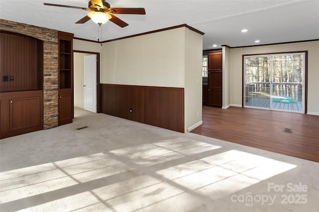 empty room with ceiling fan, light colored carpet, and crown molding