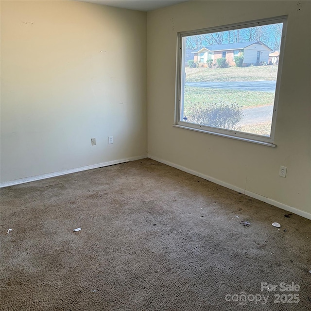 carpeted empty room featuring baseboards