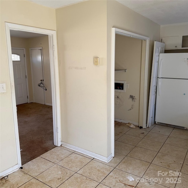 hall featuring light tile patterned floors, baseboards, and light colored carpet