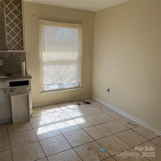 unfurnished dining area featuring baseboards and light tile patterned flooring