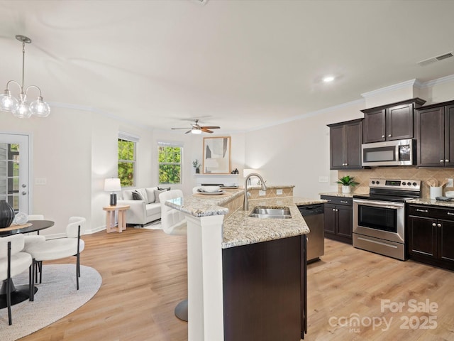 kitchen with dark brown cabinetry, sink, decorative light fixtures, decorative backsplash, and appliances with stainless steel finishes