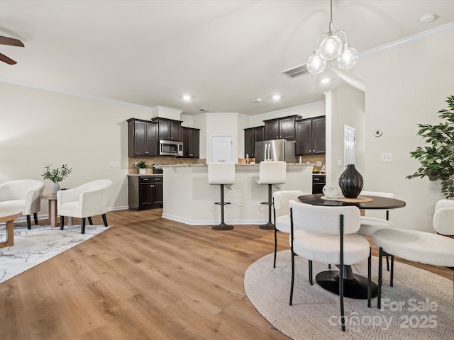 kitchen featuring decorative backsplash, a kitchen bar, light wood-type flooring, stainless steel appliances, and a kitchen island