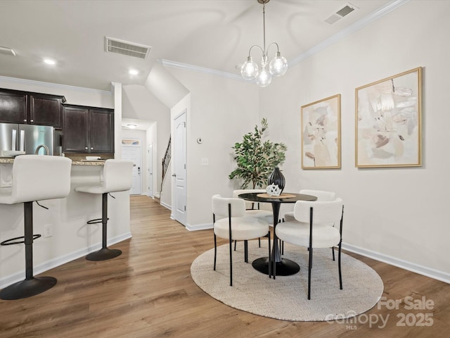 dining area featuring ornamental molding, light hardwood / wood-style floors, and a notable chandelier