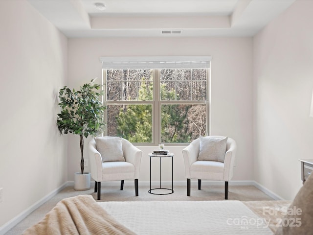 living area with a tray ceiling and light colored carpet