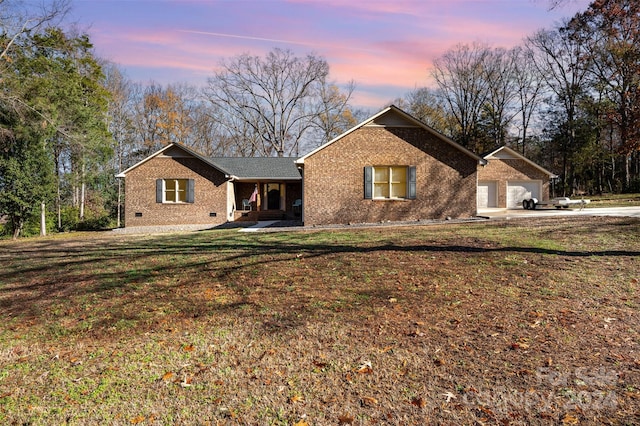 back house at dusk with a lawn and a garage