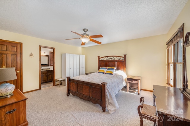 carpeted bedroom with a textured ceiling, a closet, ensuite bath, and ceiling fan