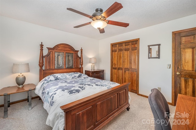 bedroom with ceiling fan, a closet, light colored carpet, and a textured ceiling