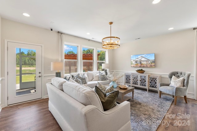 living room with dark hardwood / wood-style flooring, plenty of natural light, and a notable chandelier