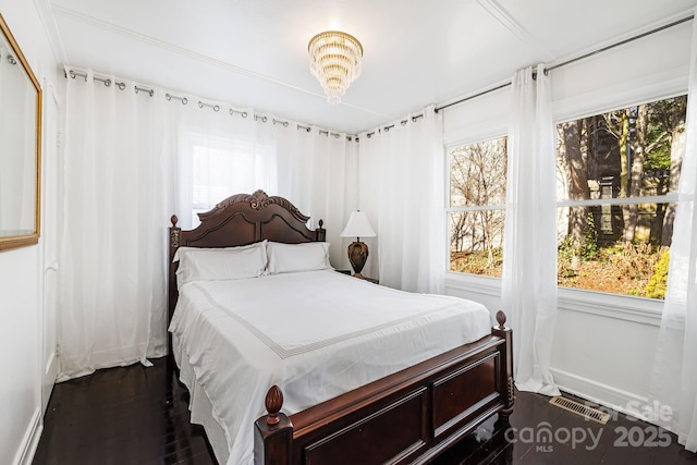 bedroom with an inviting chandelier and dark hardwood / wood-style flooring